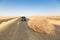 A car stopped by a giant tumbleweed on a highway with sandy dunes, between Bahariya oasis and Farafra, Western Desert of Egypt.