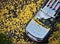 Car strewn with autumn yellow leaves in October on a wet sidewalk