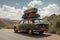 a car, with suitcases on top of the roof rack and a road sign in the background