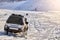 Car SUV drives through a snow-covered mountain valley with deep snow after a snowstorm.