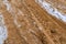 Car Tire Marks on an Empty Field Covered With Snow, closeup view - Cloudy Day