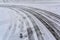 Car tire traces on the snow with human steps traces beside.