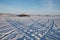 Car tracks go across the frozen Great Lake to the island against the backdrop of the village of Parnaya, Krasnoyarsk Territory.