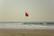 Car tracks on a yellow sandy beach near a red flag prohibiting swimming amid ocean waves under a clear blue sky