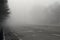 Car traveling on the foggy road with headlights or headlamps on. Low visibility - Dangerous driving of cars in winter in bad