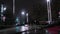 Car travels through night city streets in the rain