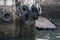 Car tyres hanging on rope against harbour wall at port dock to protect ships and boats