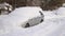 Car under thick blanket of snow after storm. Vehicles buried under ice. Nobody