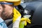 Car wash employee covering his nose with hand and using bottle with disinfection liquid to neutralize stink from air duct vent