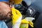 Car wash employee covering his nose with hand and using bottle with disinfection liquid to neutralize stink from air duct vent