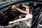 Car wash service, girl worker cleans leather surface of steering wheel with rag