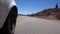 Car wheel moving down fast the winding paved road on desert area, with cactus around. Close up view