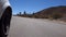 car wheel moving down fast the winding paved road on desert area, with cactus around. Close up view