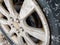 Car wheel with snow stuck to it. Closeup view. Rusted drum brakes