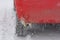 Car wheel with spikes on snowy road in winter. Icicles on bumper red car. Concept dangerous driving in extreme cold and bad