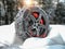 Car wheel with winter tire and snow chain in snow forest