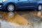 Car wheels in a puddle of rainwater, raindrops and water circles. Winter weather in Israel