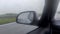 Car wing mirror view during a heavy rainy drive