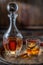 Carafe of whisky and glass of whisky on old wooden cask at the dark background