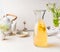 Carafe with white tea citrus lemonade drink on white kitchen table. Summer beverage concept