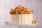 Caramel drip cake decorated with popcorn and pretzels on light background, closeup