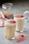 Caramel latte cocktails in tall glass with rose flowers decoration on coloured cream foam