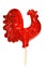 Caramel lollipop bright red very large sugar cockerel on a white background, a traditional children`s treat