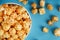 Caramel popcorn in a white glass cup with scissors on a blue background