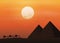 Caravan with camels in desert with pyramids on beautiful sunset background