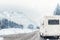 Caravan or campervan turning from road with beautiful mountain alpine landscape on background at cold winter season.Family