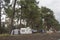 Caravan, cars and tent covered. Tourists on holiday in forest, setting a tent covered