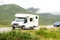 A caravan driving on a road in the landscape of Scottish Highlands in misty weather with motion blur effect