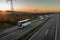 Caravan of Four white buses in line traveling on a highway at sunset