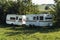 Caravan trailer camping on a green lawn under a tree in springtime