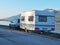 Caravan trailer by the lake in winter season travelling on the mountains