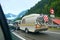 Caravan or travel trailer with hanging bicycles attached to a car on the alpine road in Swiss alps.