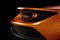 The carbon fiber body of an orange and black GT race car with its sharp curves and intricate details illuminated Speed