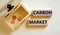 Carbon market symbol. Concept words `carbon market` on wooden blocks on a beautiful white background, small chest with coins.