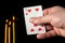 Card seven in the hand of a fortune teller close-up on a black background and burning candles candles. This is a prediction of a