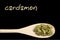 Cardamon on wooden spoon isolated on black background. Latin name Elettaria cardamomum