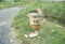 Cardboard beer cartons on the ground next to a trash can with the words ï¿½Earth Dayï¿½ painted on its side