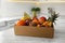 Cardboard box with assortment of exotic fruits on table in kitchen