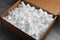 Cardboard box filled with polystyrene styrofoam pieces on grey table, closeup