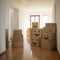 Cardboard boxes loaded with household stuff in an empty room at a moving day. Moving boxes stacked in empty room ready for