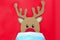 Cardboard cutout of cute reindeer peeking while wearing a face mask. Covid during Christmas season concept.