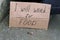 Cardboard plate next to unemployed sitting on concrete with i will work for food coins lie nearby on a ground