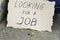 Cardboard plate next to unemployed sitting on concrete with looking for a job coins lie nearby on a ground
