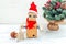 Cardboard robot with hands in santa hat on a white wooden background and christmas tree. Christmas composition