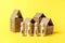 Cardboard toy houses on yellow background with help sign. Falling property prices. Economic depression