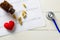 Cardiogram with stethoscope, pill and red heart on table